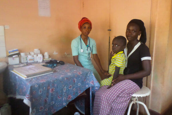 A health care worker attends to a Gambian woman and her daughter at a child health clinic