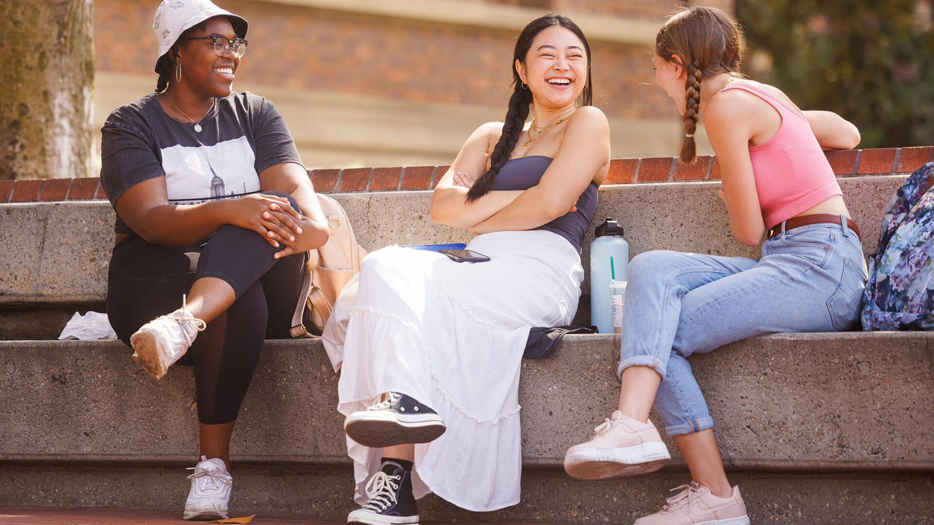 Three diverse USC students laughing and sitting together outdoors on campus steps, USC Global