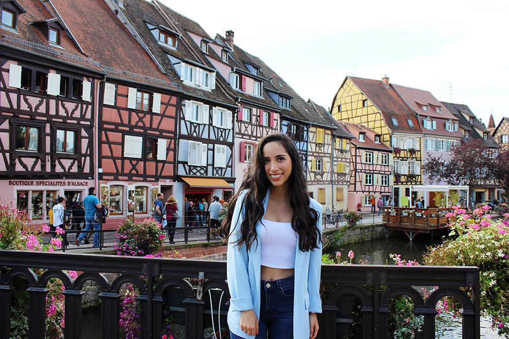 USC student experiencing the historic charm of Colmar, France with traditional half-timbered houses along the canal.